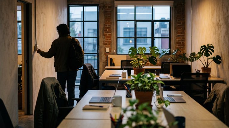 Espacio de trabajo pequeño a primera hora, con escritorios vacíos y luz cálida