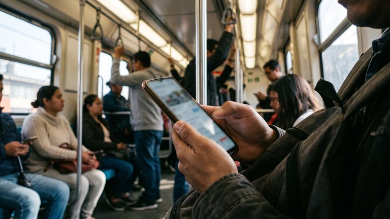 Persona desplazándose en su teléfono dentro de un vagón de metro